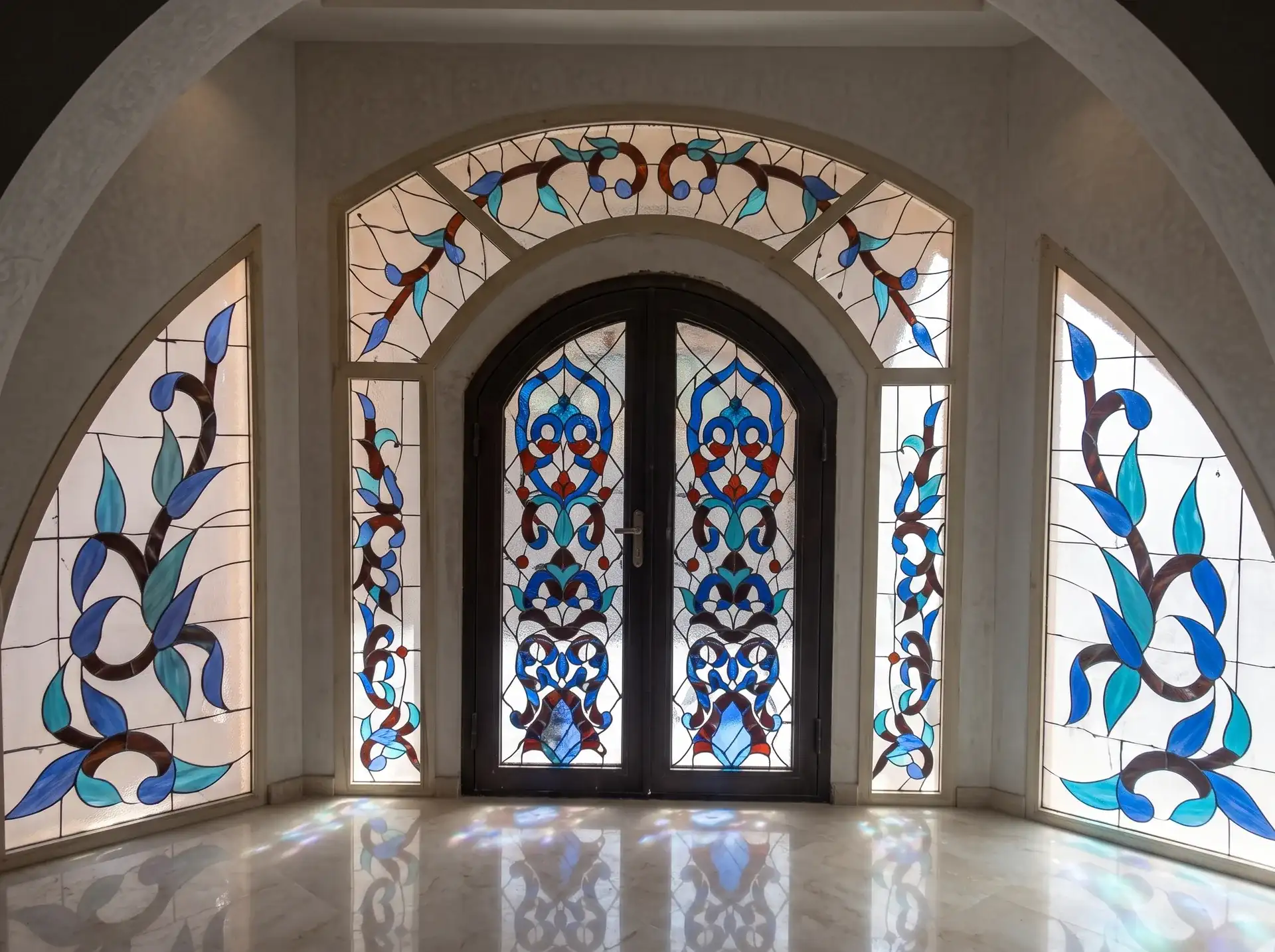 مدخل مقوس بنوافذ وأبواب زجاج معشق بزخارف زرقاء