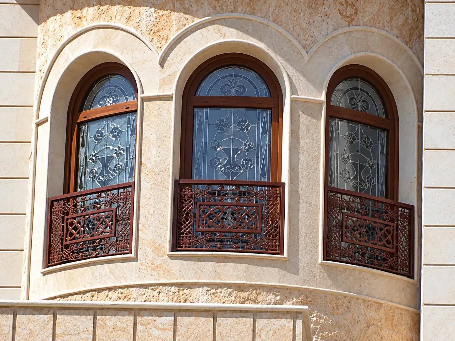 واجهة حجرية بثلاث نوافذ مقوسة وزجاج مزخرف وشرفات خشبية